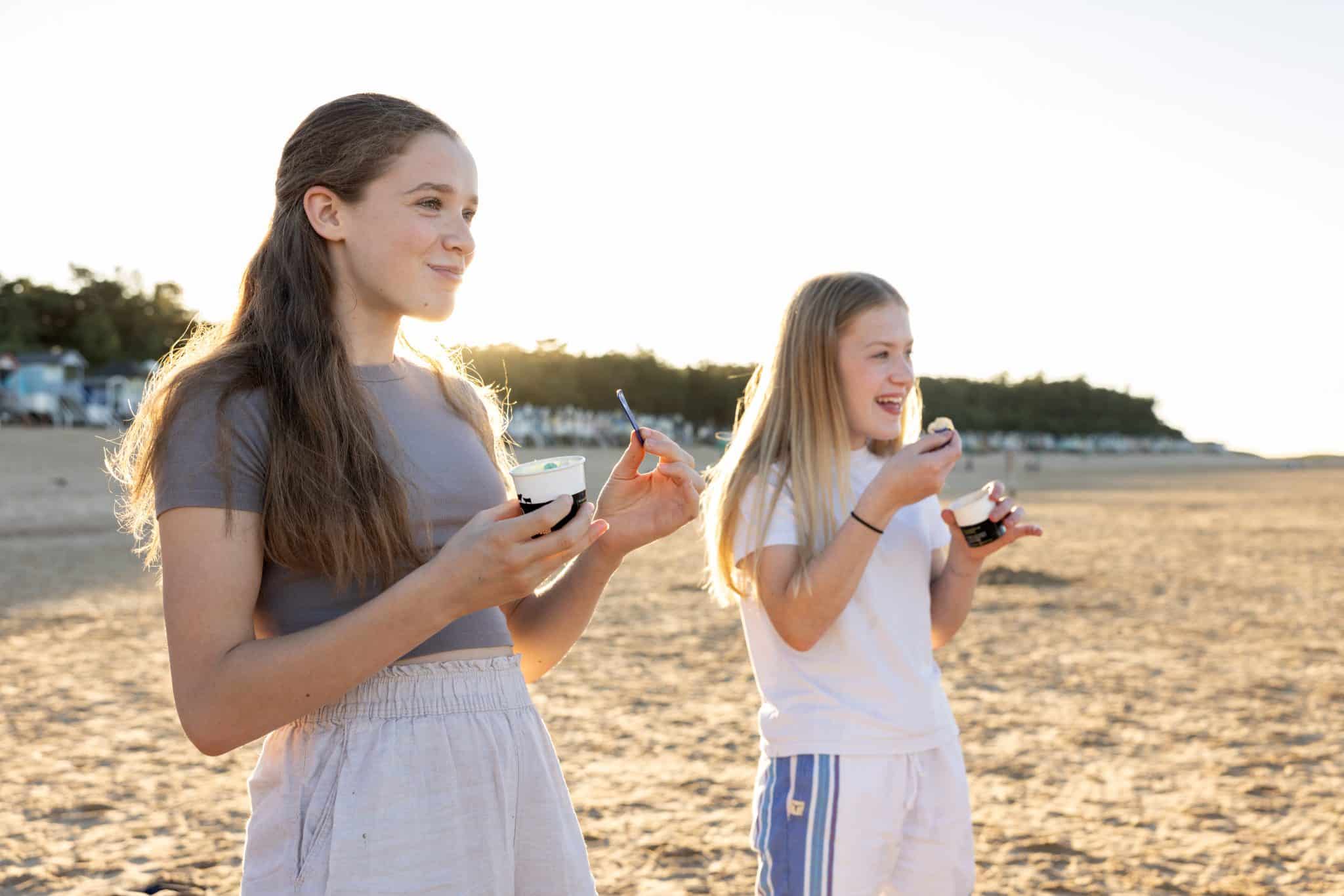 Two teenage girls eat ice cream on Wells Beach.