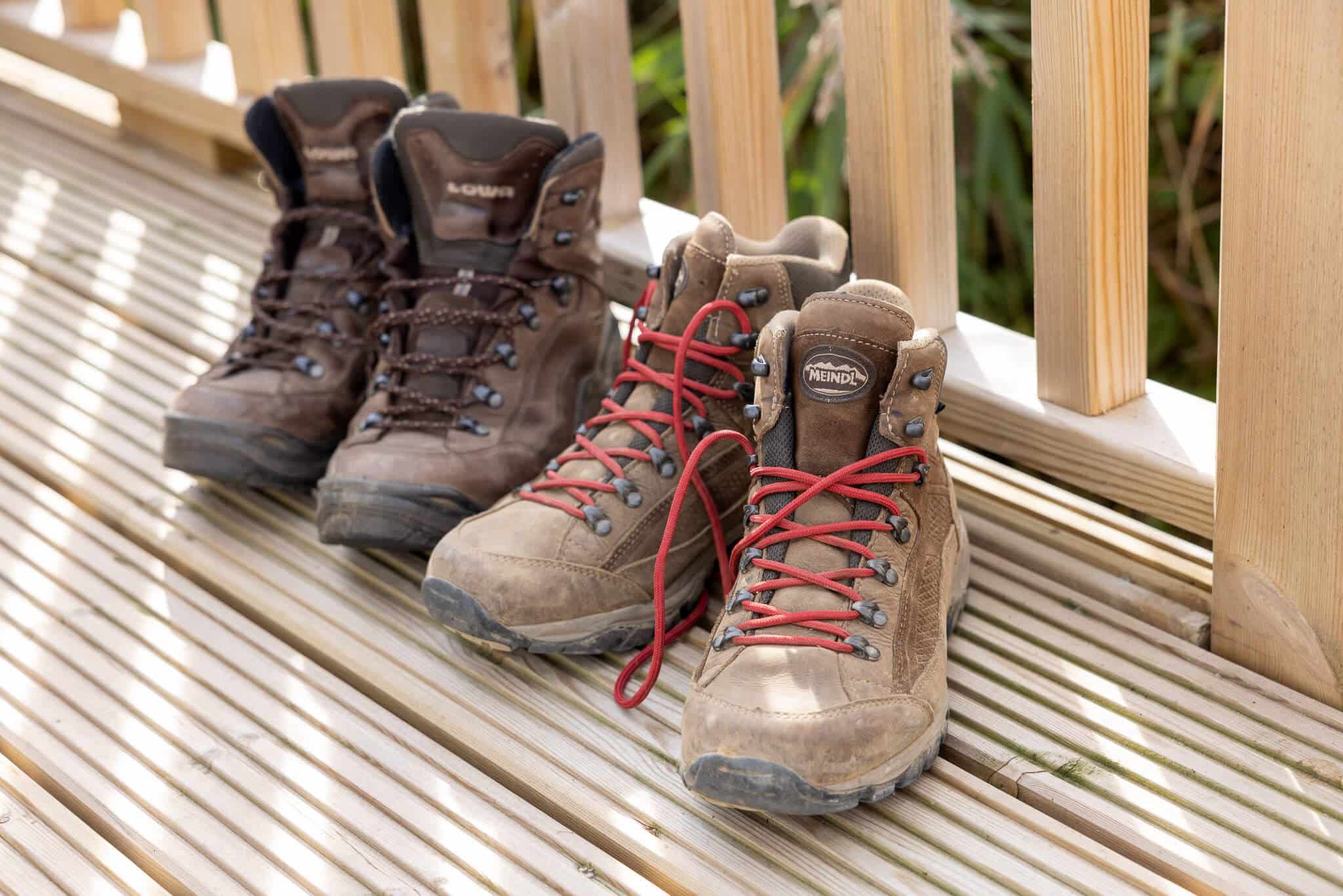 Two pairs of brown walking boots sit on the decking.